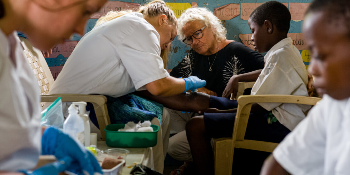 Ruth Nesje assisting a student in cleaning up a childs wound